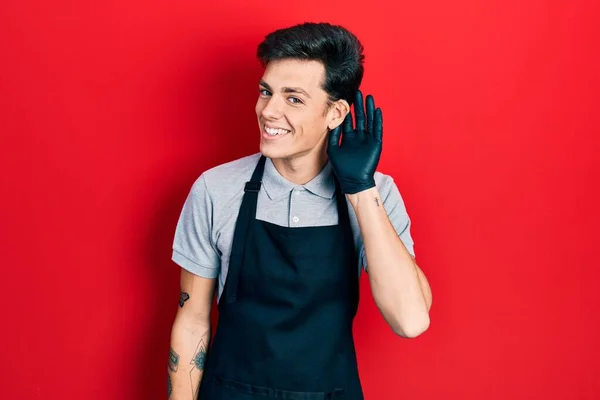 Jovem Hispânico Vestindo Avental Sorrindo Com Mão Sobre Ouvido Ouvindo — Fotografia de Stock