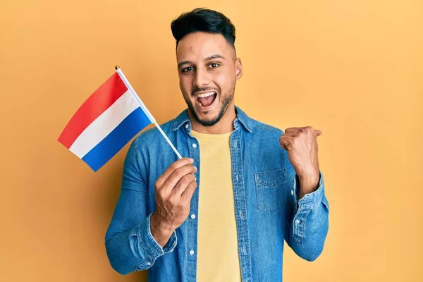Hollanda Bayrağını Tutan Genç Arap Adam Başparmağını Yana Kaldırmış Ağzı — Stok fotoğraf