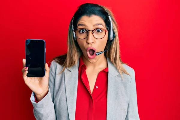 Beautiful Brunette Woman Wearing Operator Headset Showing Smartphone Screen Scared — Stock Photo, Image