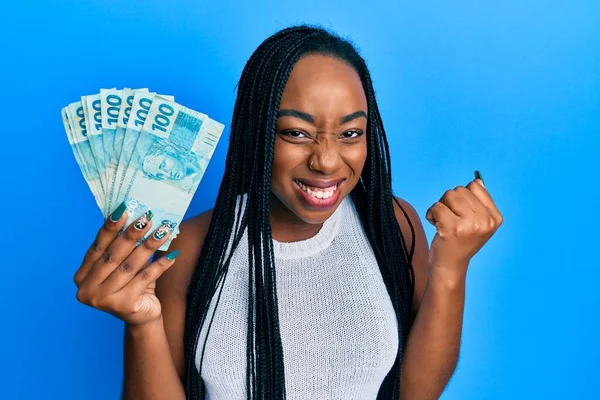 Joven Mujer Afroamericana Sosteniendo 100 Billetes Reales Brasileños Gritando Orgullosos —  Fotos de Stock