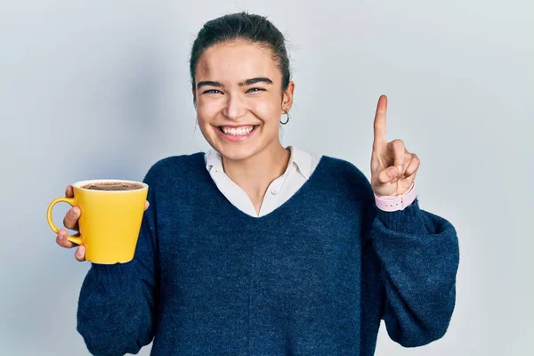 年轻的高加索女孩微笑着端着咖啡 满脸喜形于色地指指点点 位居第一 — 图库照片