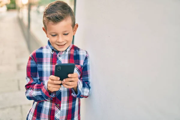 Beyaz Çocuk Şehirde Akıllı Telefon Kullanarak Mutlu Bir Şekilde Gülümsüyor — Stok fotoğraf