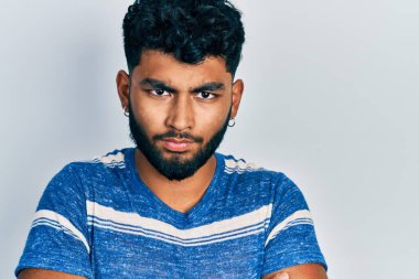 Sıradan çizgili tişört giyen, kuşkucu ve gergin sakallı bir Arap. Yüzünde çapraz kollu tasvip etmeyen bir ifade var. negatif kişi. 