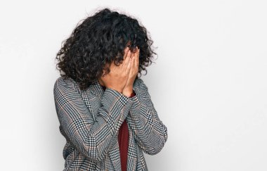 Ağlarken yüzünü ellerle kapatan üzgün bir ifadeyle iş kıyafetleri giyen genç İspanyol kadın. depresyon kavramı. 