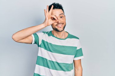 Gündelik kıyafetler giyen genç İspanyol adam el hareketleriyle gülümsüyor ve mutlu yüzüyle parmaklarından bakıyor.. 