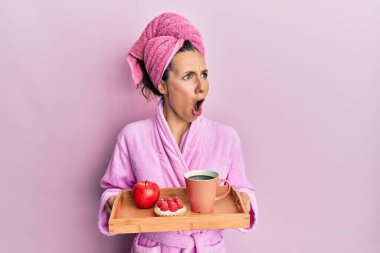 Genç, sarışın bir kadın, elinde bornoz tepsisiyle kahvaltı tepsisi tutuyordu. Öfkeli ve öfkeli çığlıklar atıyordu. Öfkeyle bağırıyordu. öfke ve agresif konsept. 
