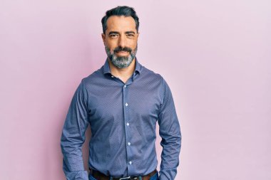 Orta yaşlı, sakallı, gri saçlı iş kıyafetleri giyen mutlu ve havalı bir gülümsemesi olan bir adam. şanslı kişi. 