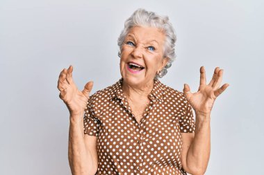 Son sınıf gri saçlı, günlük kıyafetler giyen çılgın ve kızgın bir kadın agresif bir ifadeyle bağırıyor ve kollarını kaldırıyor. hüsran kavramı. 