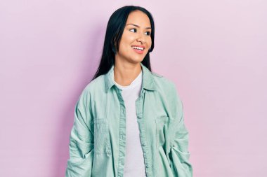 Güzel İspanyol kadın, burun piercingli, sıradan yeşil ceket giyen rahat bir profil pozu veren, doğal yüzlü ve kendine güvenen bir gülümseme takınıyor.. 