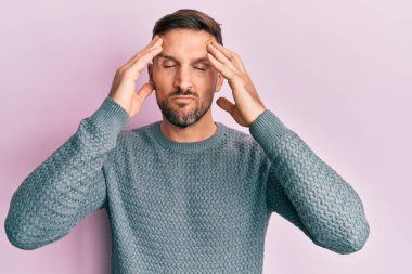 Sakallı, sıradan bir kazak giyen, eli kafasında, başı ağrıyan yakışıklı bir adam. migren ağrısı. 