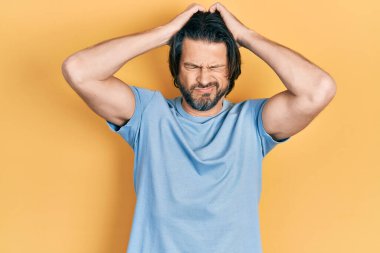 Orta yaşlı, günlük kıyafetler giyen, baş ağrısı çeken, çaresiz ve stresli bir adam. Ağrı ve migren yüzünden. Eller başının üstünde.. 