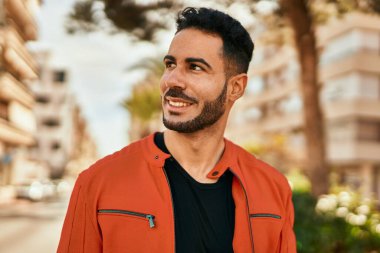 Genç İspanyol adam gülümseyerek şehirde mutlu mesut dikiliyor..