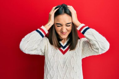Genç esmer kız gündelik kazak giyiyor. Baş ağrısı çekiyor, çaresiz ve stresli. Çünkü acı ve migren ağrısı var. Eller başının üstünde.. 