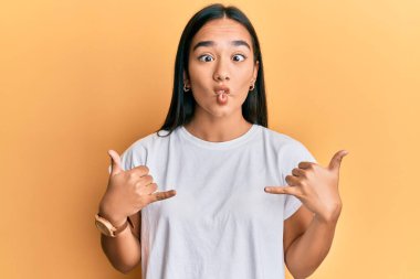 Genç Asyalı kadın elleriyle shaka işareti yapıyor ağızlarıyla balık suratı yapıyor ve şaşı bakıyor, çılgın ve komik.. 