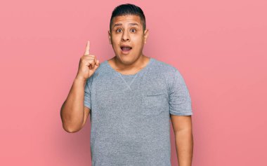 Gündelik kıyafetler giyen genç latin adam başarılı bir fikri işaret ediyor. Heyecanlı ve mutlu. Bir numara.. 