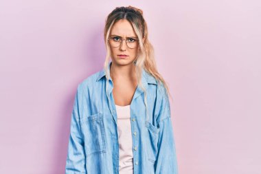 Gündelik kıyafetler giyen, gözlüklü, kuşkucu ve gergin genç, güzel sarışın bir kadın sorun yüzünden surat asıyor. negatif kişi. 