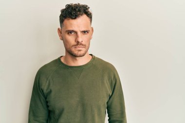 Gündelik kıyafetler giyen, kuşkucu ve gergin genç İspanyol bir adam sorun yüzünden surat asıyor. negatif kişi. 