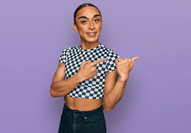 Makyaj yapan, uzun saçlı, modern kıyafetler giyen, gülümseyen ve kameraya bakan İspanyol transseksüel bir adam.. 