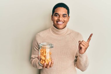 Genç, yakışıklı İspanyol adam elinde makarna kavanozuyla gülümsüyor. 