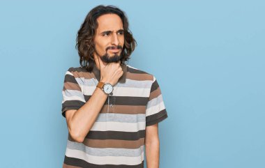 Günlük giysiler giyen genç İspanyol adam ağrılı boyuna dokunuyor, grip, mantar ve enfeksiyon yüzünden boğaz ağrısı çekiyor. 