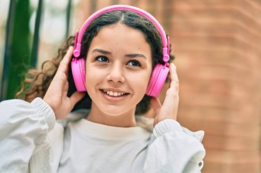 Şehirde kulaklık takıp gülümseyen İspanyol çocuk..