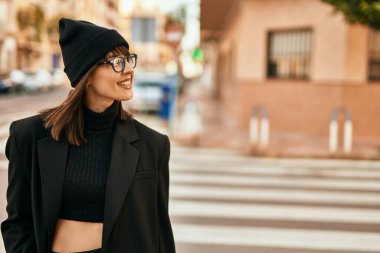 Genç İspanyol kadın gülümseyerek şehirde mutlu mesut dikiliyor..