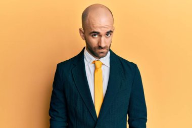 Genç İspanyol bir adam iş elbisesi giyiyor ve kravat takıyor şüpheci ve gergin, sorun yüzünden surat asıyor. negatif kişi. 