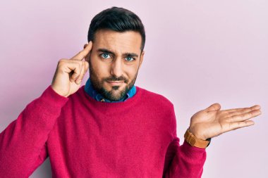 Gündelik giysiler giyen genç İspanyol adam avuç içi açık fotokopi alanı gösterip alnını işaret etmekten rahatsız oluyor. Bunu bir düşün.. 