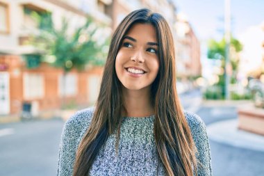 Genç ve güzel İspanyol kız gülümseyerek şehirde mutlu mesut yürüyor..