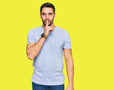 Gündelik kıyafetler giyen genç İspanyol adam parmakları dudaklarında sessiz olmak istiyor. sessizlik ve gizli konsept. 