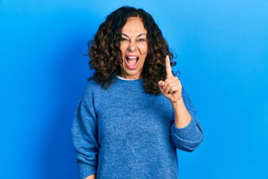 Orta yaşlı İspanyol kadın gündelik giysiler giyip başarılı bir fikri işaret ediyor. Heyecanlı ve mutlu. Bir numara.. 