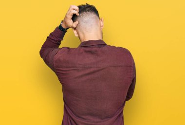 Latin asıllı genç adam gündelik kıyafetleri ters giyip elleri kafasında şüpheyi düşünüyor. 