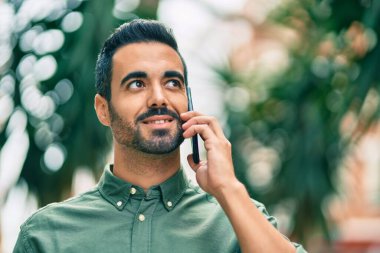 Genç İspanyol adam gülümsüyor. Şehirdeki akıllı telefondan konuşuyor..