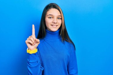 Balıkçı yaka kazak giyen genç esmer kız başarılı bir fikri işaret ediyor. Heyecanlı ve mutlu. Bir numara.. 