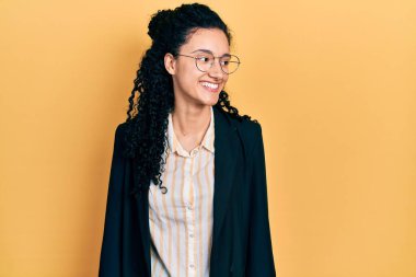 Kıvırcık saçlı, iş elbiseleri giyen, yüzünde gülümsemeyle yan yana bakan genç İspanyol kadın, doğal ifade. Kendinden emin gülen. 