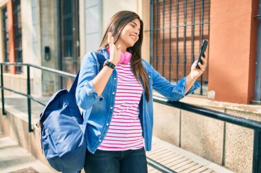 Genç İspanyol öğrenci gülümseyerek şehirde akıllı telefon kullanarak video araması yapıyor..