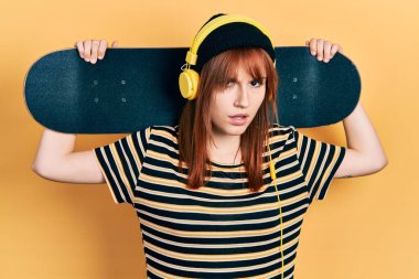 Kızıl saçlı, elinde kulaklık takan, kafası karışık ve kafası karışık genç bir kadın. şüphe kavramı. 
