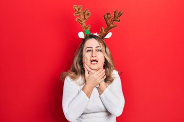 Orta yaşlı beyaz kadın şirin Noel geyiği boynuzları takıyor ve boğularak can çekişiyor çünkü boğularak can veriyor. Sağlık problemi. Boğulma ve intihar konsepti. 