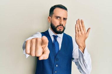 Sakallı genç adam nişan yüzüğü takıyor. Parmağını kameraya doğrultuyor. Kendine güvenin tam. 