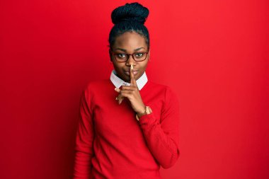 Sıradan kıyafetler ve gözlük takan Afro-Amerikalı genç bir kadın sessiz olmak istiyor. sessizlik ve gizli konsept. 