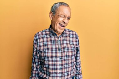 Gri saçlı, sıradan tişörtlü yakışıklı bir adam kameraya seksi bir ifadeyle bakıyor, neşeli ve mutlu bir yüzü var.. 