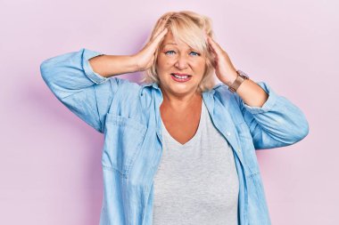 Orta yaşlı, sıradan kıyafetler giyen, baş ağrısı çeken, çaresiz ve stresli bir kadın. Ağrı ve migren yüzünden. Eller başının üstünde.. 