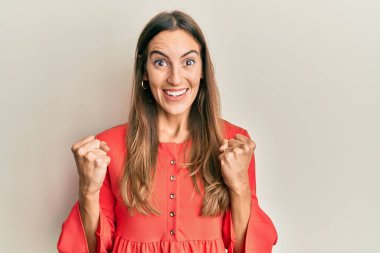 Gündelik giysiler giyen genç ve güzel bir kadın şaşkınlık ve şaşkınlık içinde kollarını kaldırarak ve gözlerini açarak başarıyı kutluyor. Kazanan konsept. 