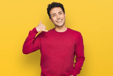 Genç, yakışıklı, sıradan kıyafetler giymiş, gülümseyen, el ve parmaklarıyla telefonla konuşan bir adam. iletişim kavramları. 