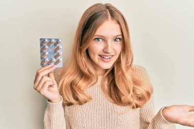 Güzel beyaz kız elinde haplarla başarıyı mutlu bir gülümsemeyle kutluyor ve kazanan el kaldırarak ifade ediyor. 