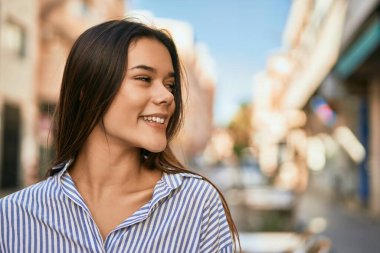 Genç İspanyol kız gülümseyerek şehirde mutlu mesut dikiliyor..