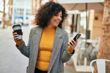 Genç İspanyol iş kadını akıllı telefon kullanıyor. Şehirde kahve içiyor..