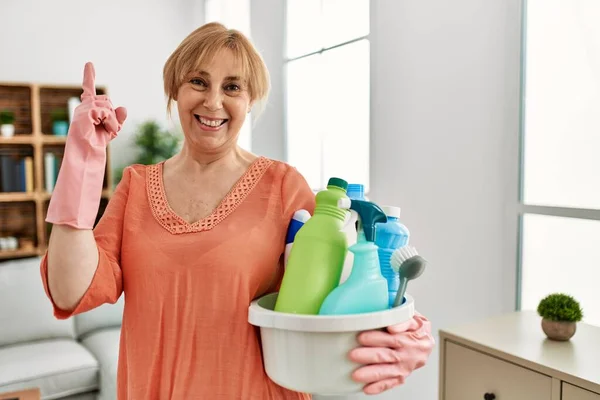 Mulher Loira Meia Idade Segurando Produtos Limpeza Limpeza Casa Surpreso — Fotografia de Stock