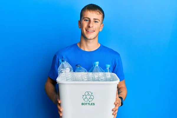 プラスチックボトルでリサイクルゴミ入れを持っている若い白人男性は笑顔で大声で笑います面白いクレイジージョークので — ストック写真