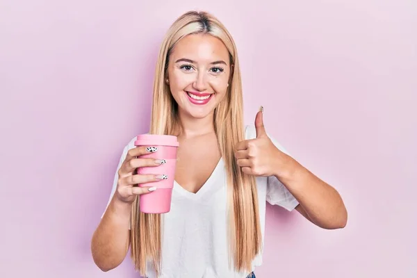 Menina Loira Jovem Segurando Café Sorrindo Feliz Positivo Polegar Para — Fotografia de Stock